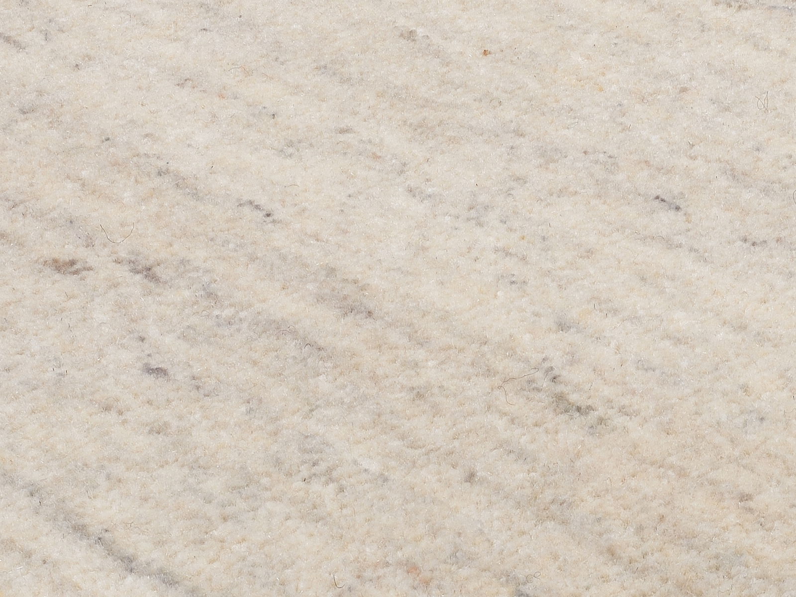 Nahaufnahme eines Wollteppichs in cremefarbenen Tönen mit leichter Textur.