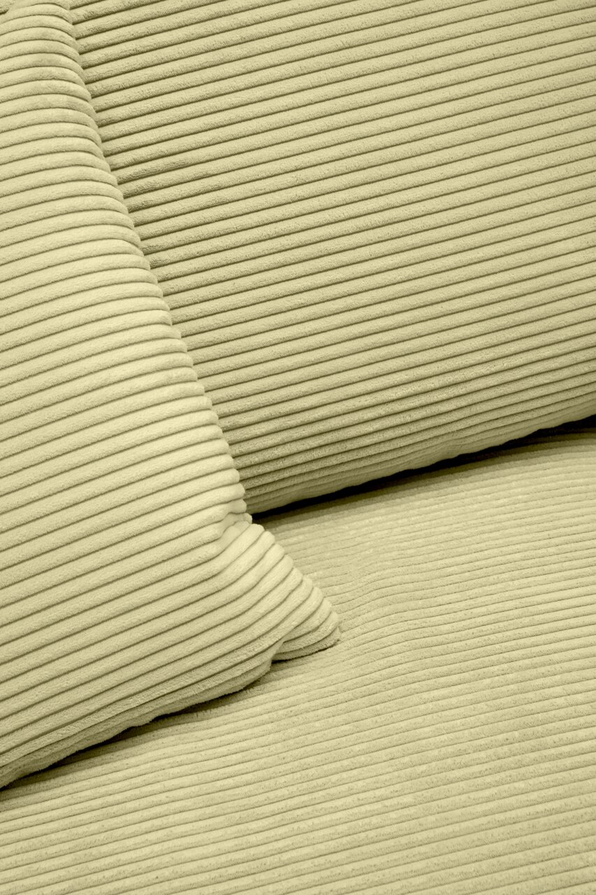 Nahaufnahme einer hellgrünen, gerippten Stoffoberfläche mit Kissen, perspektivisch von oben betrachtet.