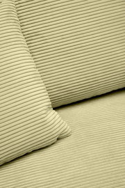 Nahaufnahme einer hellgrünen, gerippten Stoffoberfläche mit Kissen, perspektivisch von oben betrachtet.