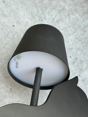 Schwarze Akku-Tischleuchte von unten fotografiert, zeigt den Lampenschirm und den Ständer auf grauem Hintergrund.