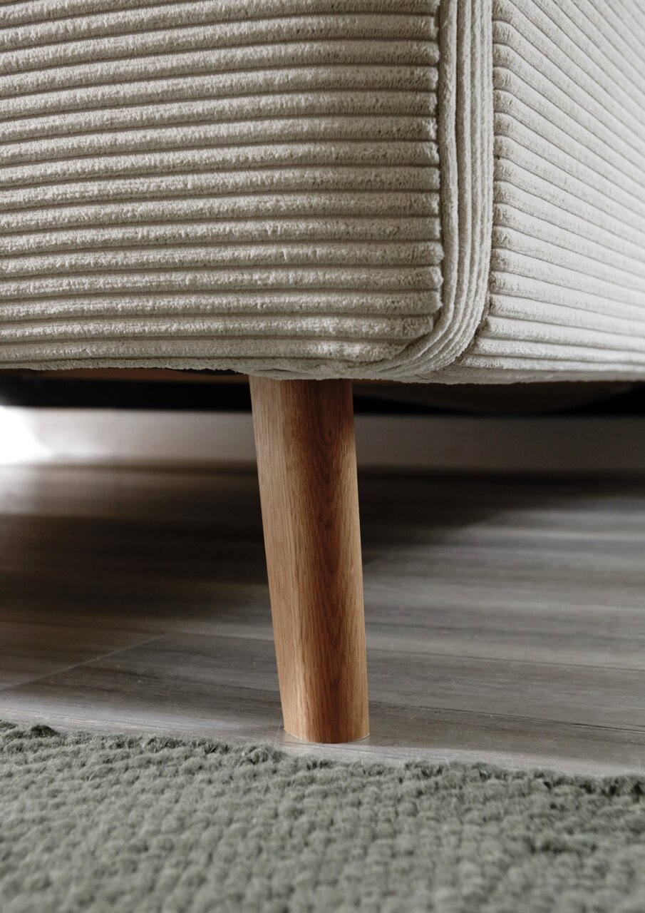 Nahaufnahme eines Polsterbettgestells mit Holzbein, seitliche Perspektive