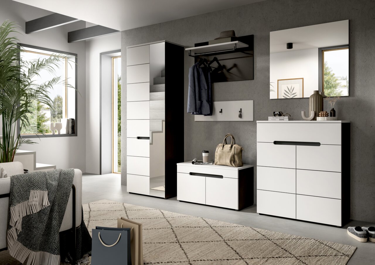 Modernes Flur-Set in Weiß mit schwarzen Griffleisten: hoher Garderobenschrank, Sitzbank/Schuhbank, Wandgarderobe mit Hutablage und Spiegel über einer Kommode, gezeigt in schräger Frontansicht im hellen Eingangsbereich.