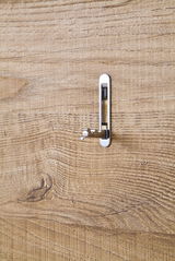 Nahaufnahme eines Holzpaneels mit einem silbernen Haken in seitlicher Perspektive.