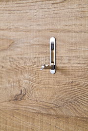 Nahaufnahme eines Holzpaneels mit einem silbernen Haken in seitlicher Perspektive.