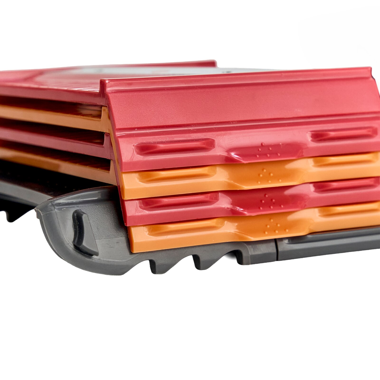 Stapel farbiger Kunststoffboxen/Organizer in Rot und Orange auf grauer Basis, Nahaufnahme aus schräger Seitenansicht.