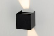 Schwarze LED-Wandleuchte in quadratischer Form, die sowohl nach oben als auch nach unten Licht abstrahlt. Perspektive von vorne leicht seitlich.