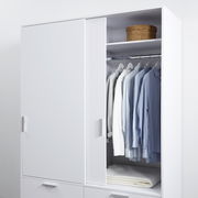 Weißer, zweitüriger Schiebetürenschrank mit geöffneter Tür, zeigt hängende Hemden und ein Fach mit einem Korb, aus frontaler Perspektive.