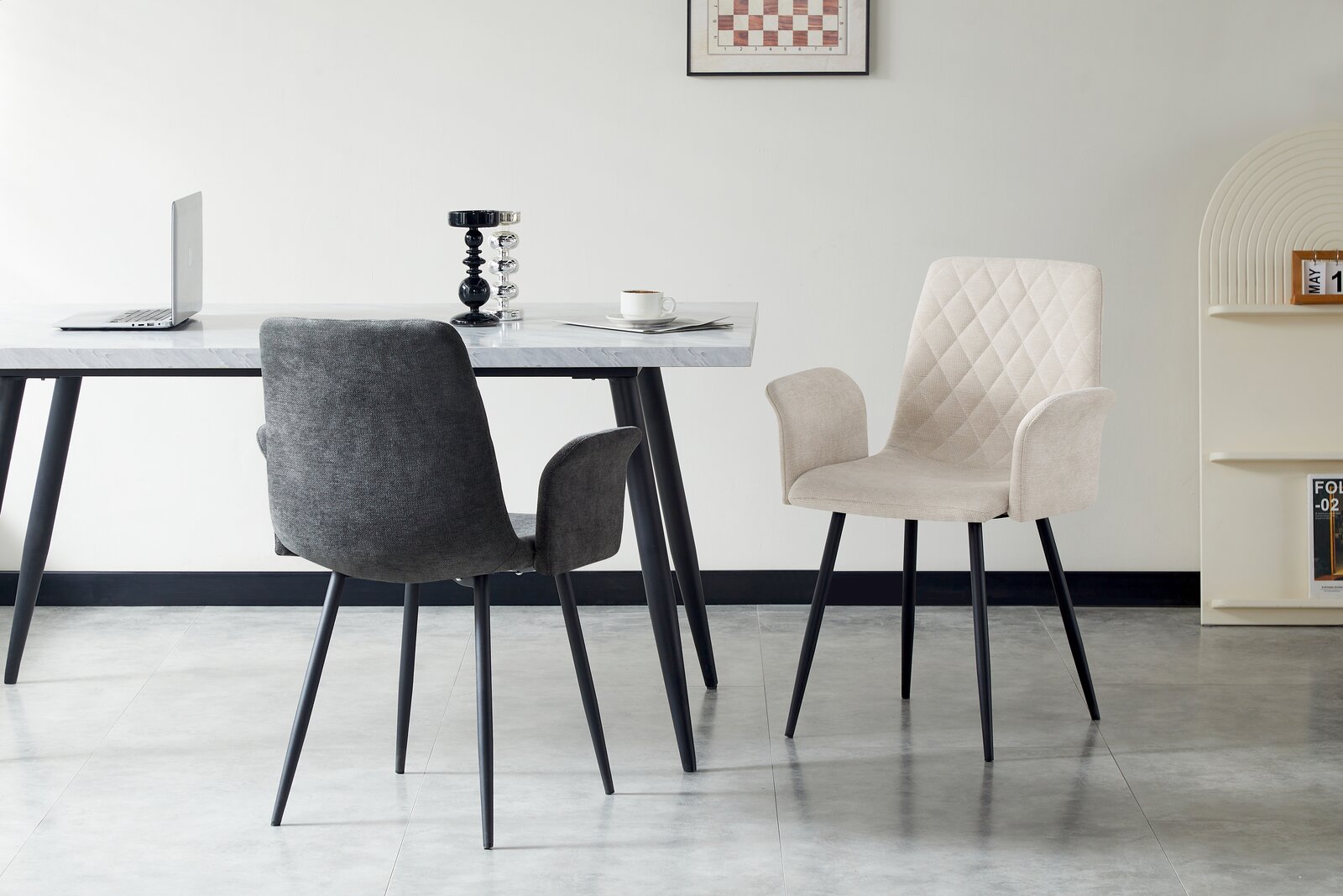Zwei Armlehnstühle in einem modernen Esszimmer, einer in dunklem Grau und der andere in hellem Beige, mit einem Tisch im Hintergrund. Perspektive von vorne.
