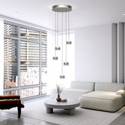Moderne LED-Pendelleuchte mit fünf hängenden Leuchtkörpern in einem stilvollen Wohnzimmer mit großen Fenstern, seitliche Perspektive.