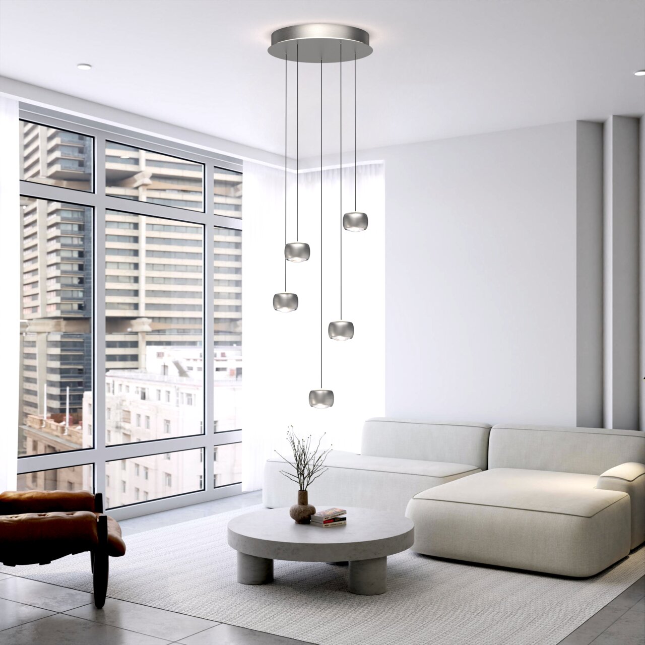 Moderne LED-Pendelleuchte mit fünf hängenden Leuchtkörpern in einem stilvollen Wohnzimmer mit großen Fenstern, seitliche Perspektive.