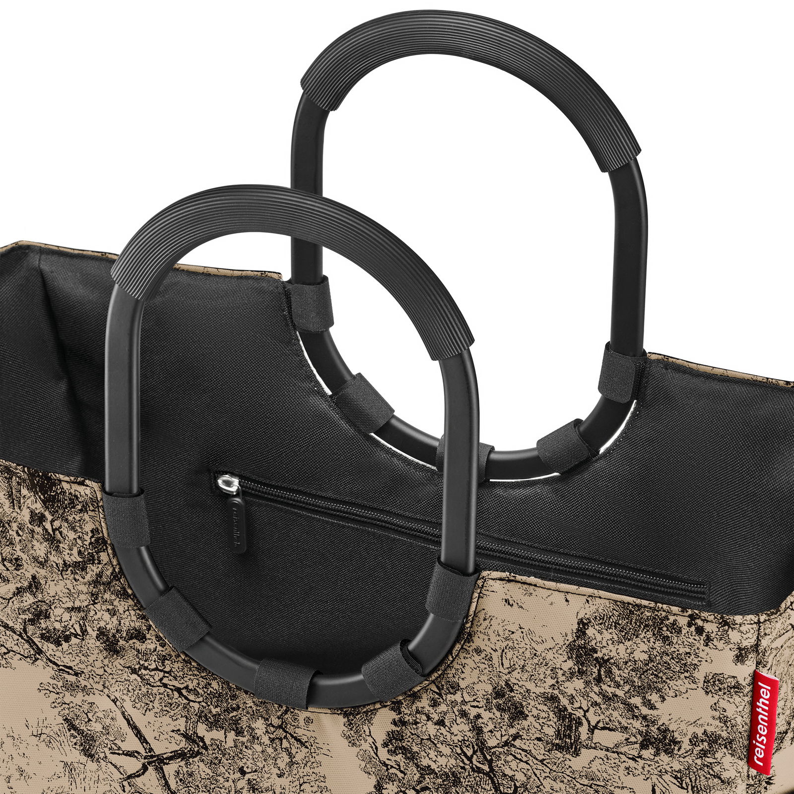 Nahaufnahme einer stilvollen Einkaufstasche mit robusten, schwarzen Griffen und einem eleganten, baumartigen Muster auf beigem Hintergrund. Perspektive von oben auf die Tasche.