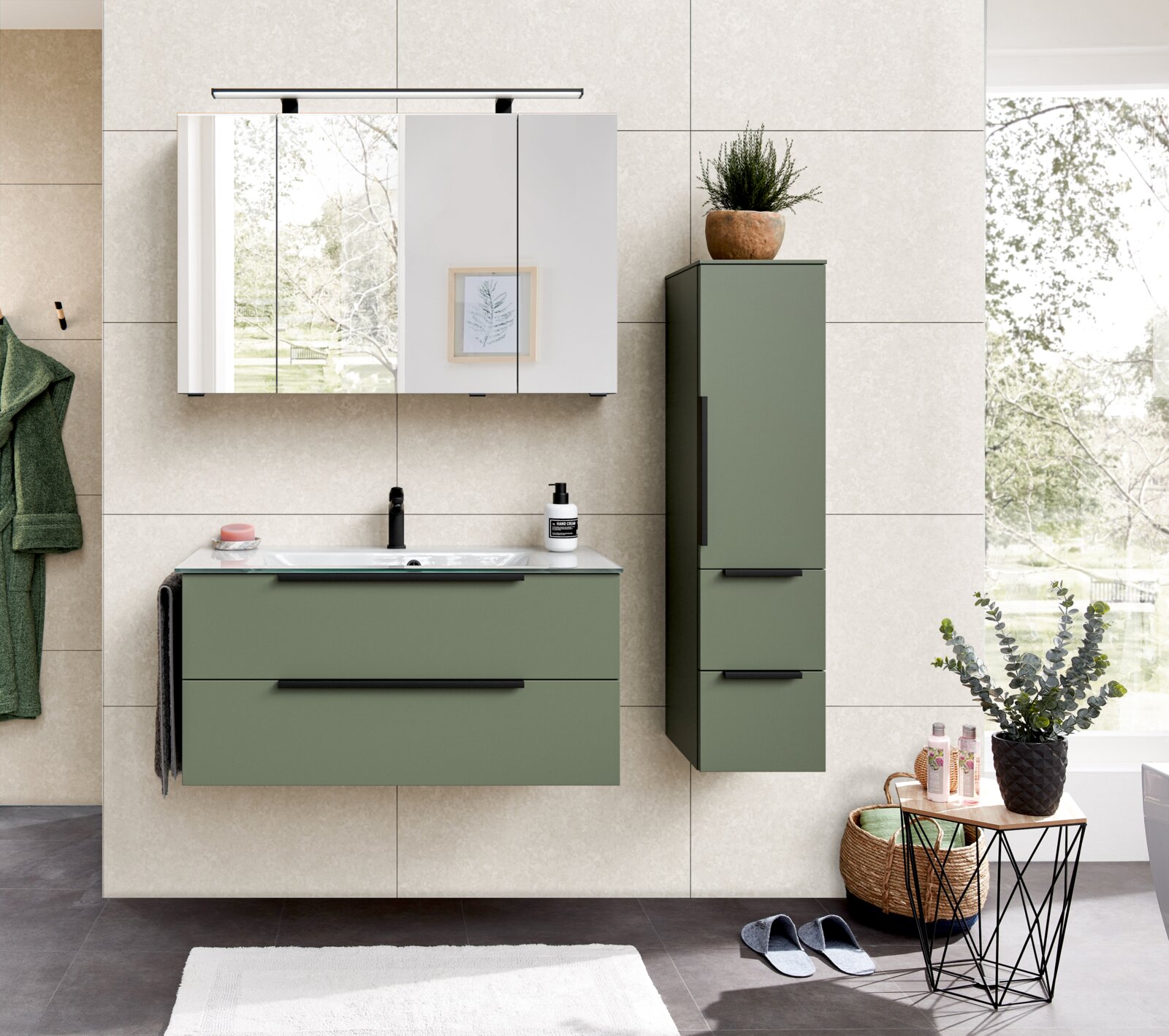 Modernes Badmöbel-Set in Salbeigrün mit hängendem Waschtischunterschrank und Hochschrank, weißem Waschtisch, schwarzer Armatur und Spiegelschrank mit Leuchte – Frontalansicht