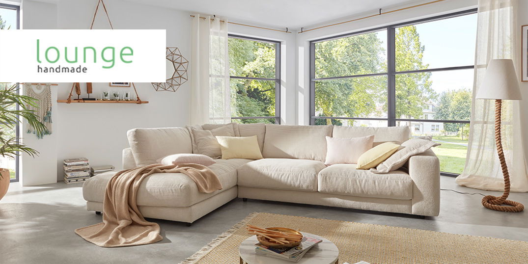 Ein helles Wohnzimmer mit einem großen, hellbeigen Sofa. Logo Lounge handmade