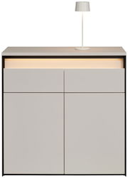 Moderne Kommode in hellem Grau mit integrierter Beleuchtung und einer Tischlampe auf der Oberseite, Frontalansicht.