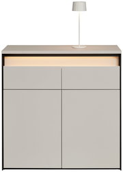 Moderne Kommode in hellem Grau mit integrierter Beleuchtung und einer Tischlampe auf der Oberseite, Frontalansicht.