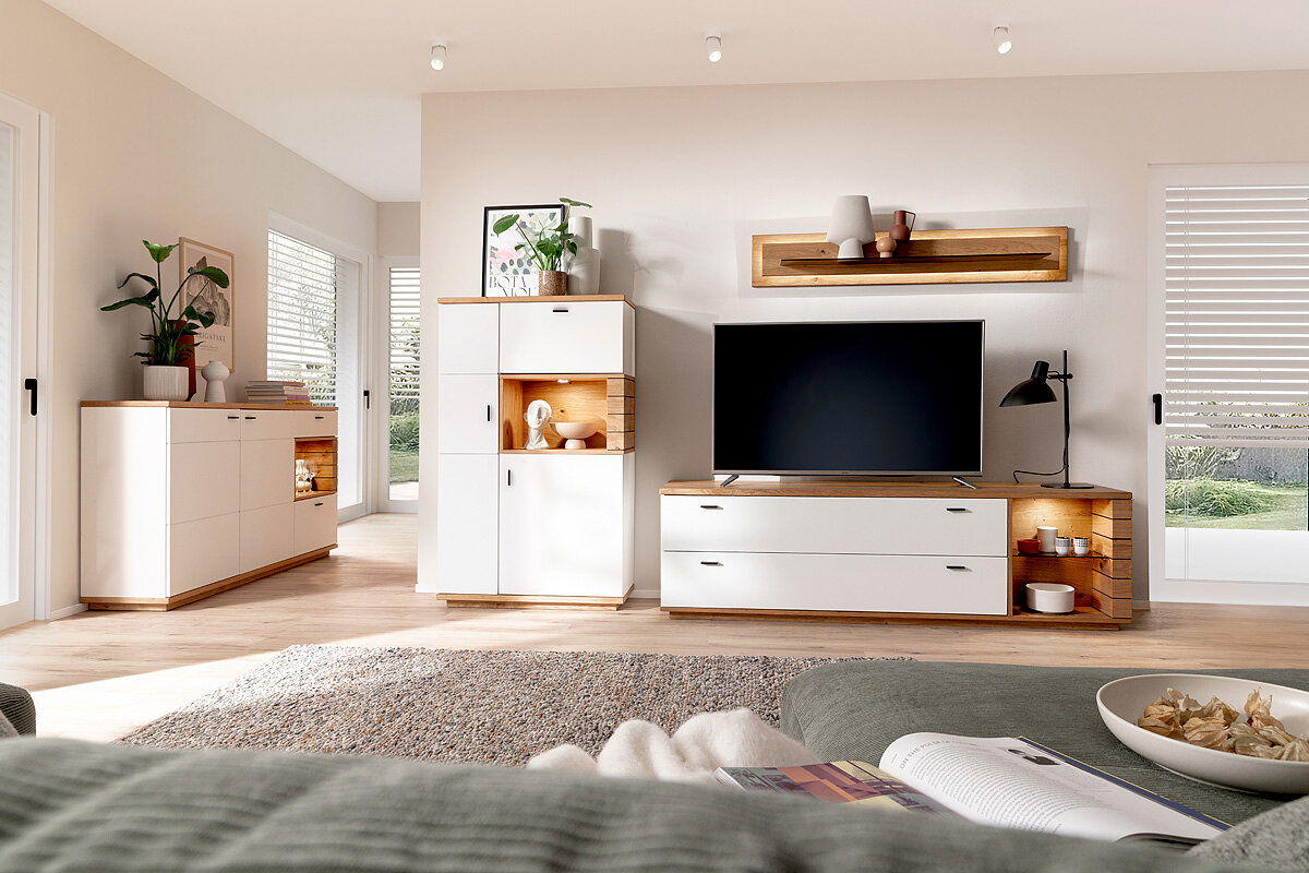 Novel Highboard MANITOBA Modernes Highboard in einem hellen Wohnzimmer, frontal betrachtet, mit weißen Türen und Holzdetails, dekoriert mit Pflanzen und Vasen.