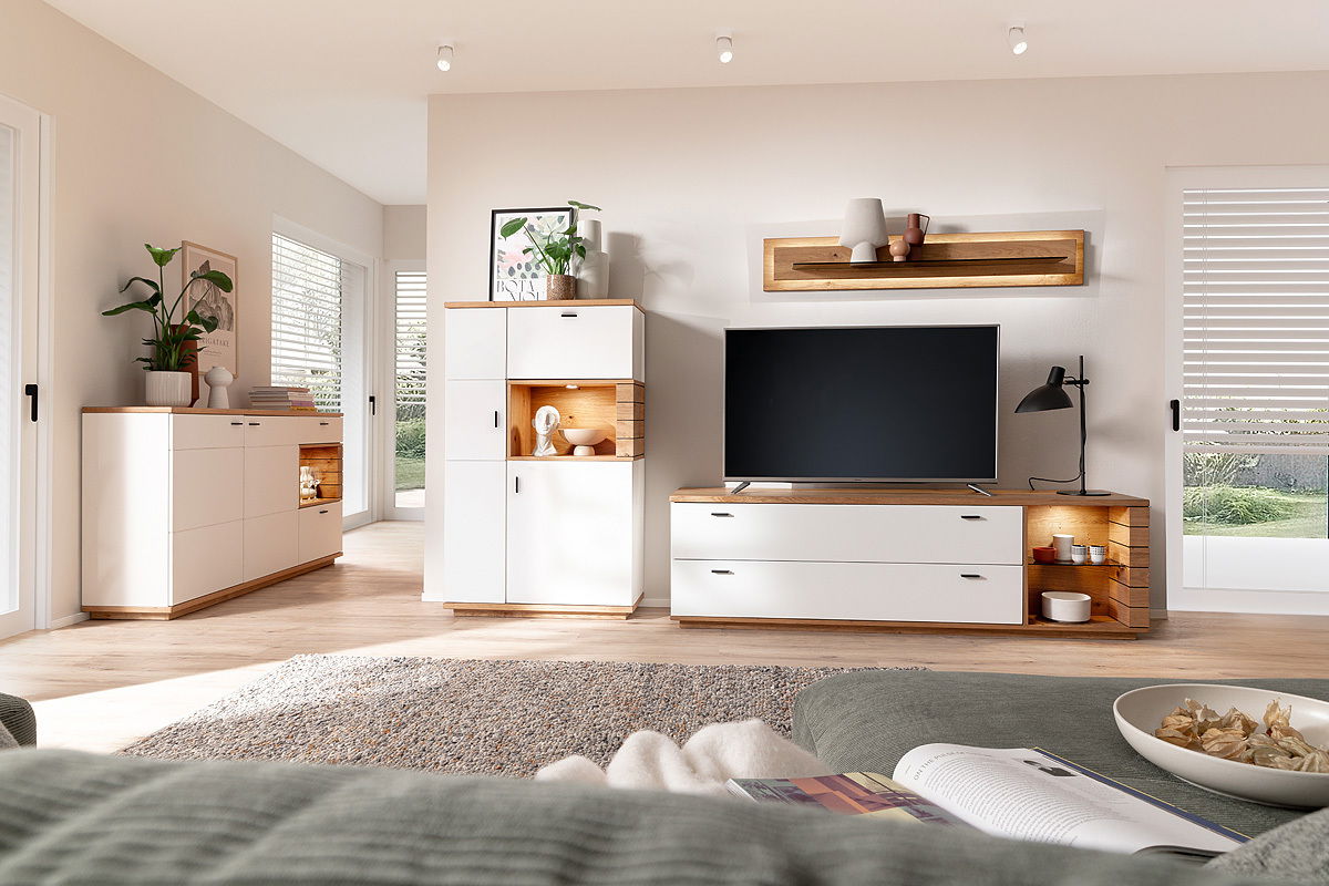 Novel Highboard MANITOBA Modernes Highboard in einem hellen Wohnzimmer, frontal betrachtet, mit weißen Türen und Holzdetails, dekoriert mit Pflanzen und Vasen.