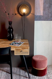 Runder, zweifarbiger Hocker in Rosa und Rot mit goldener Zierleiste, seitlich neben einem Holztisch mit schwarzem Stuhl platziert.