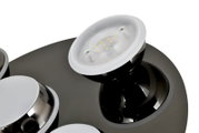 Close-up van een moderne led-plafondlamp met meerdere ronde lichtelementen op een glanzende zwarte voet, gezien vanaf de zijkant.
