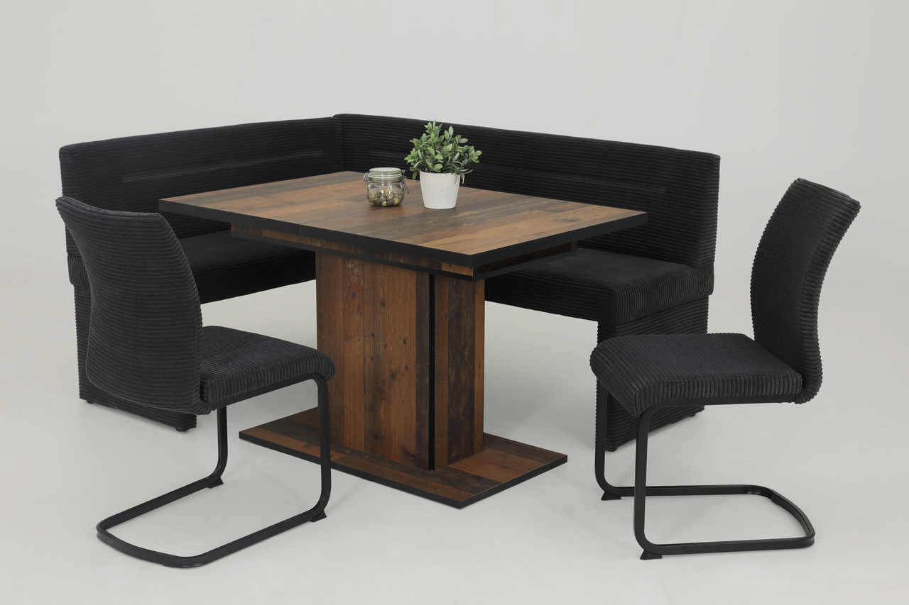 Essgruppe mit Eckbank und zwei Schwingstühlen in schwarzem Stoff, kombiniert mit einem Holztisch. Perspektive: Frontalansicht.