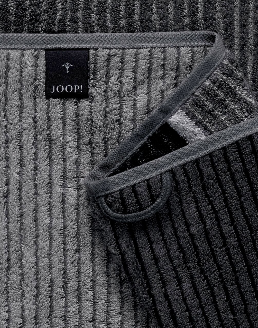 Graues gestreiftes Gästetuch von JOOP! in Nahaufnahme, mit sichtbarem Etikett und umgeschlagener Ecke.