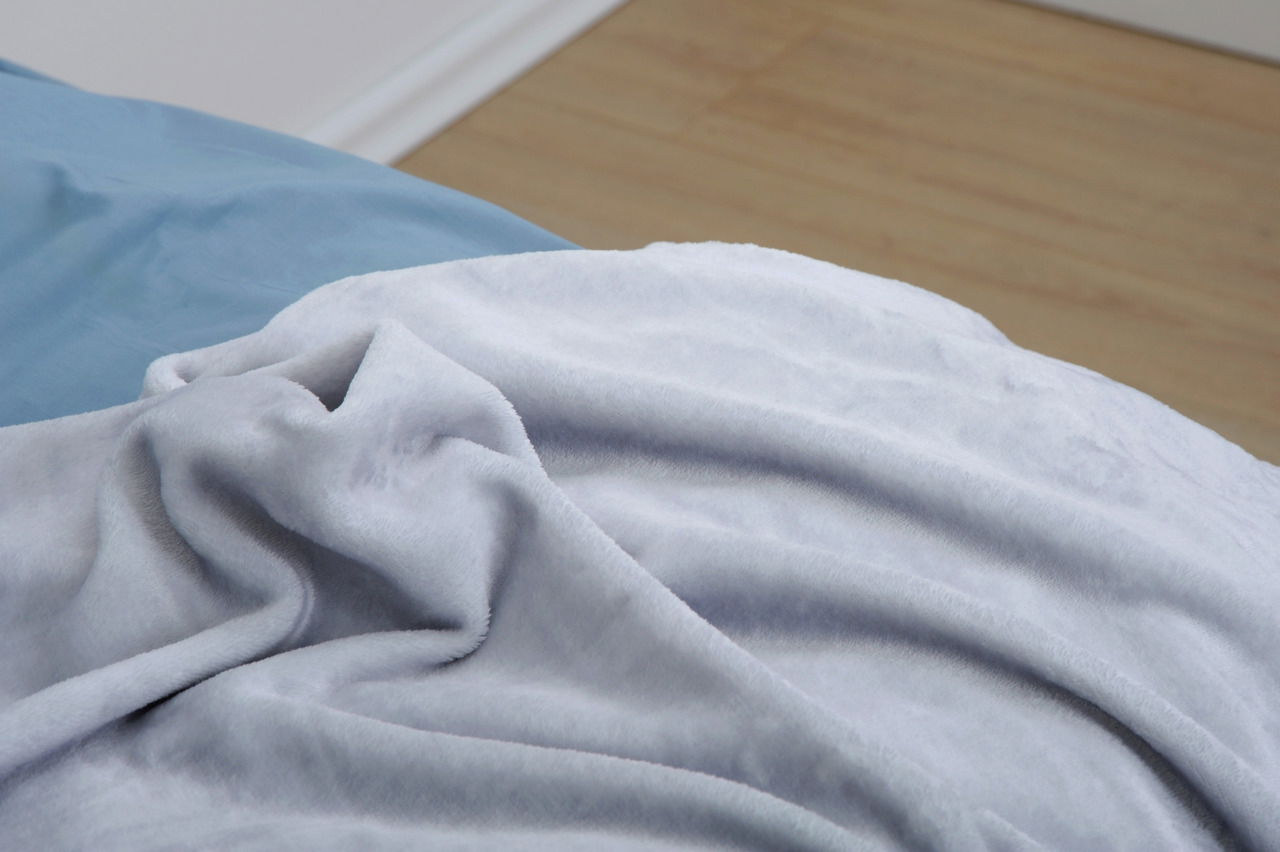 Weiche, flauschige Decke in Nahaufnahme auf einem Bett, perspektivisch von der Seite aufgenommen.
