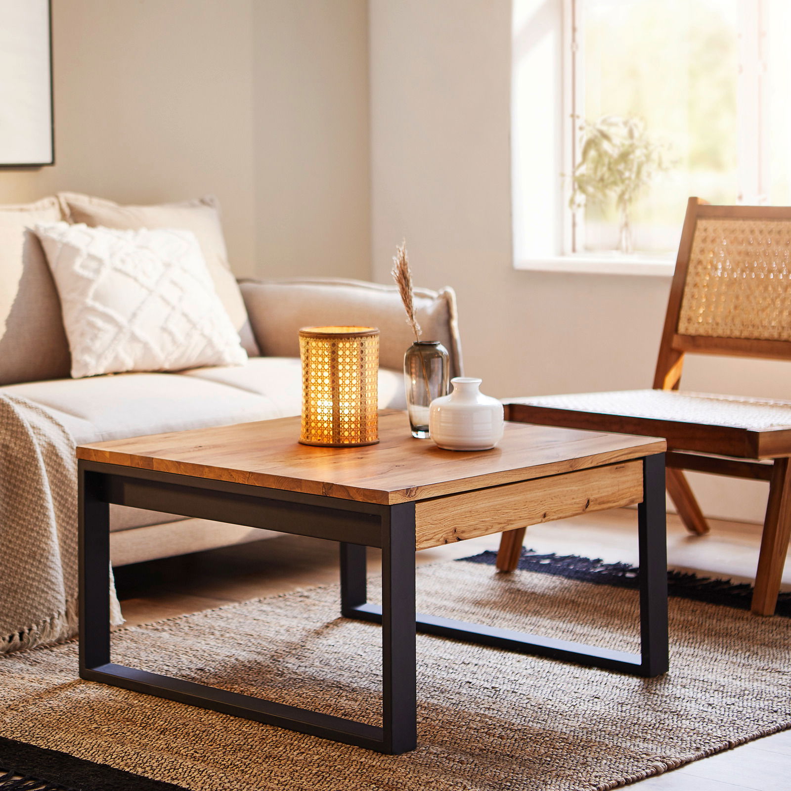 Moderner Couchtisch aus Holz mit schwarzem Metallgestell, dekoriert mit einer Lampe und Vasen, in einem gemütlichen Wohnzimmer. Perspektive: seitlich.