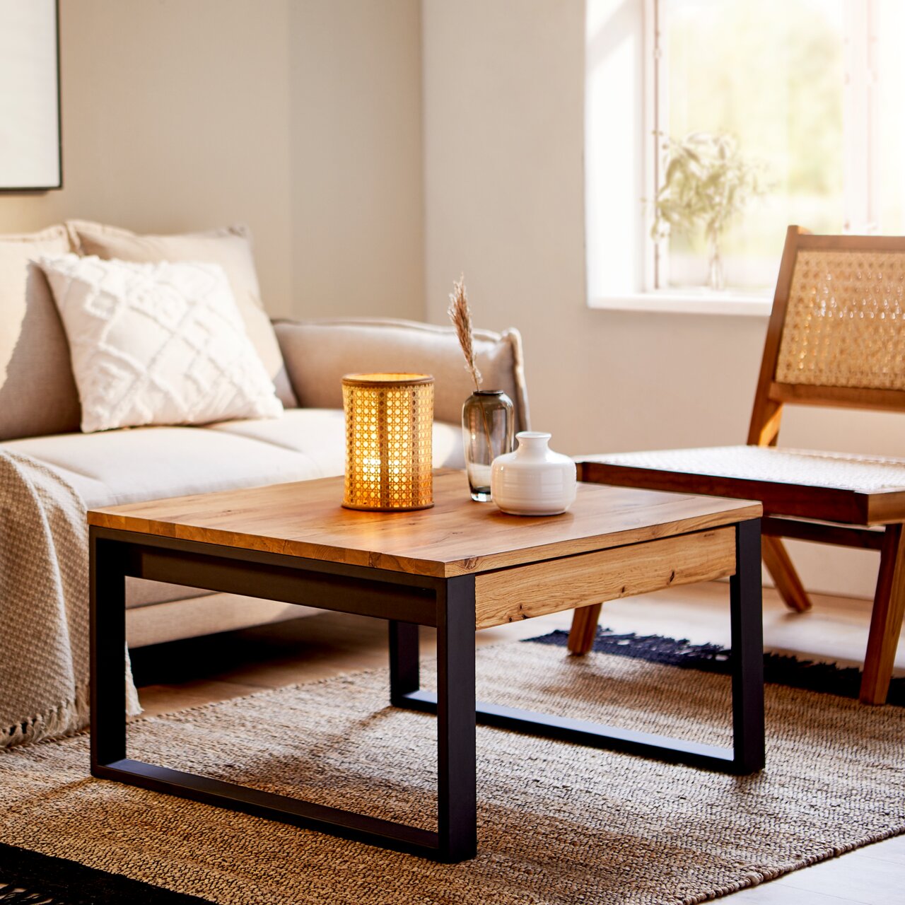 Moderner Couchtisch aus Holz mit schwarzem Metallgestell, dekoriert mit einer Lampe und Vasen, in einem gemütlichen Wohnzimmer. Perspektive: seitlich.