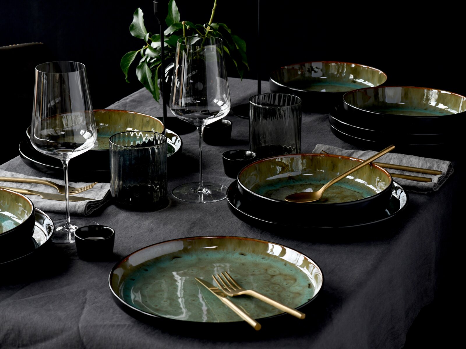 Elegantes Tafelservice 12-tlg mit grün-braunen Tellern und goldfarbenem Besteck, auf einem gedeckten Tisch von schräg oben fotografiert.