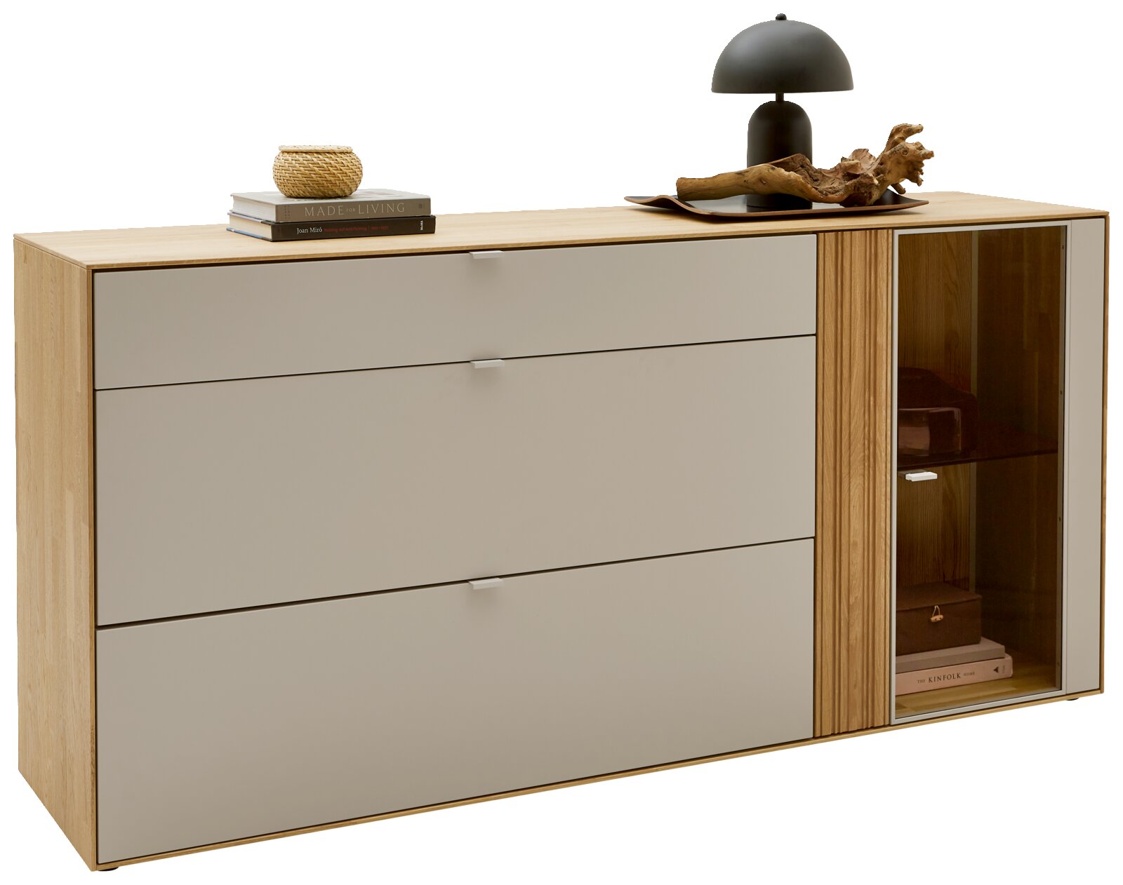 Dieter Knoll Dressoir MALEA Moderne dressoir/sideboard in licht hout met drie brede lades en een glazen vitrinedeur rechts, met decoratie op het blad; frontaal aanzicht met lichte hoek naar rechts.