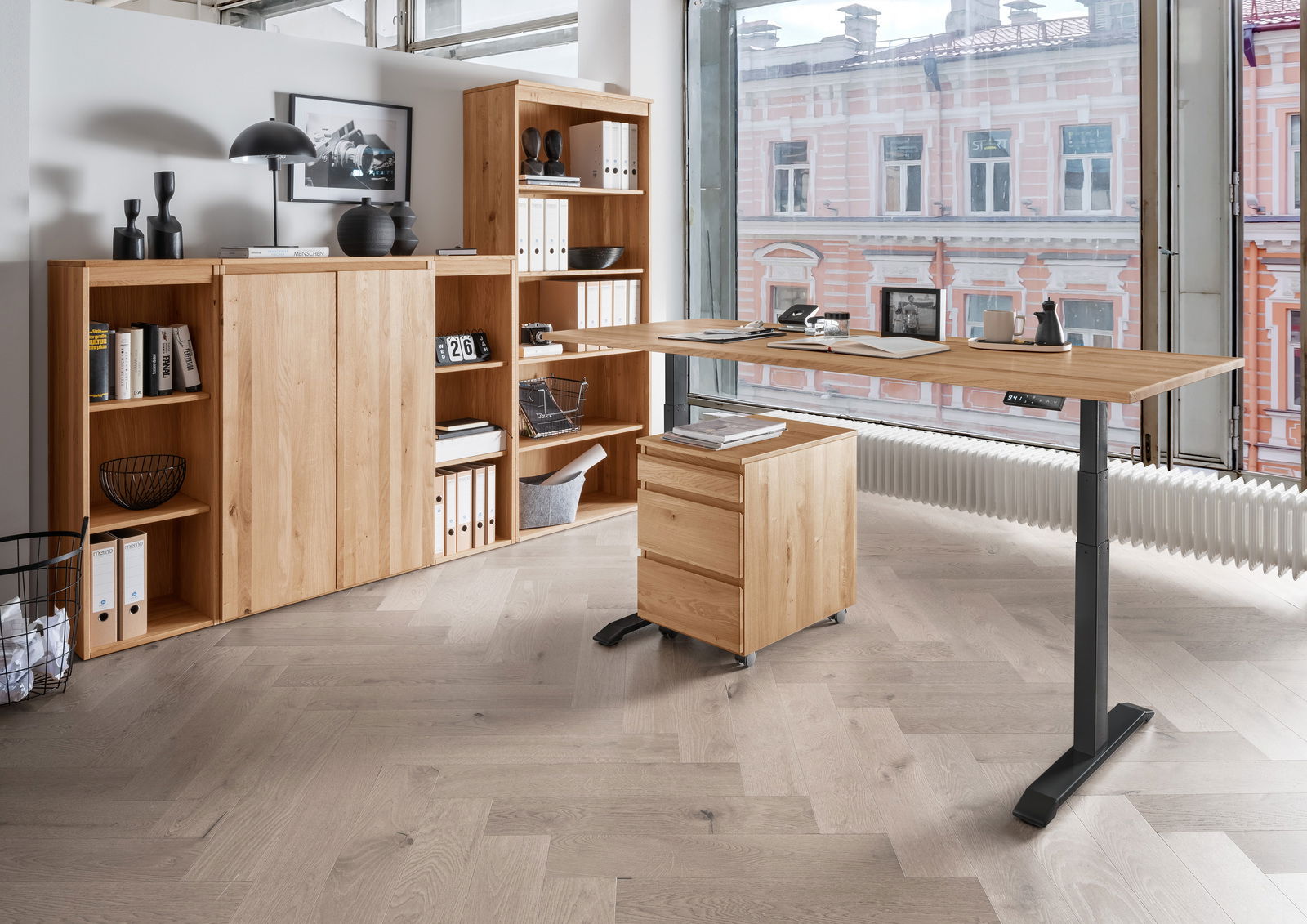 Moderne Büromöbelkombination aus Holz mit höhenverstellbarem Schreibtisch, Rollcontainer und Regalen, seitliche Perspektive.