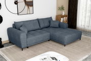 Blaues L-förmiges Ecksofa mit rechter Ottomane, breiten Armlehnen und schwarzen Metallfüßen im modernen Wohnzimmer, perspektivisch in schräger Vorderansicht von links fotografiert.