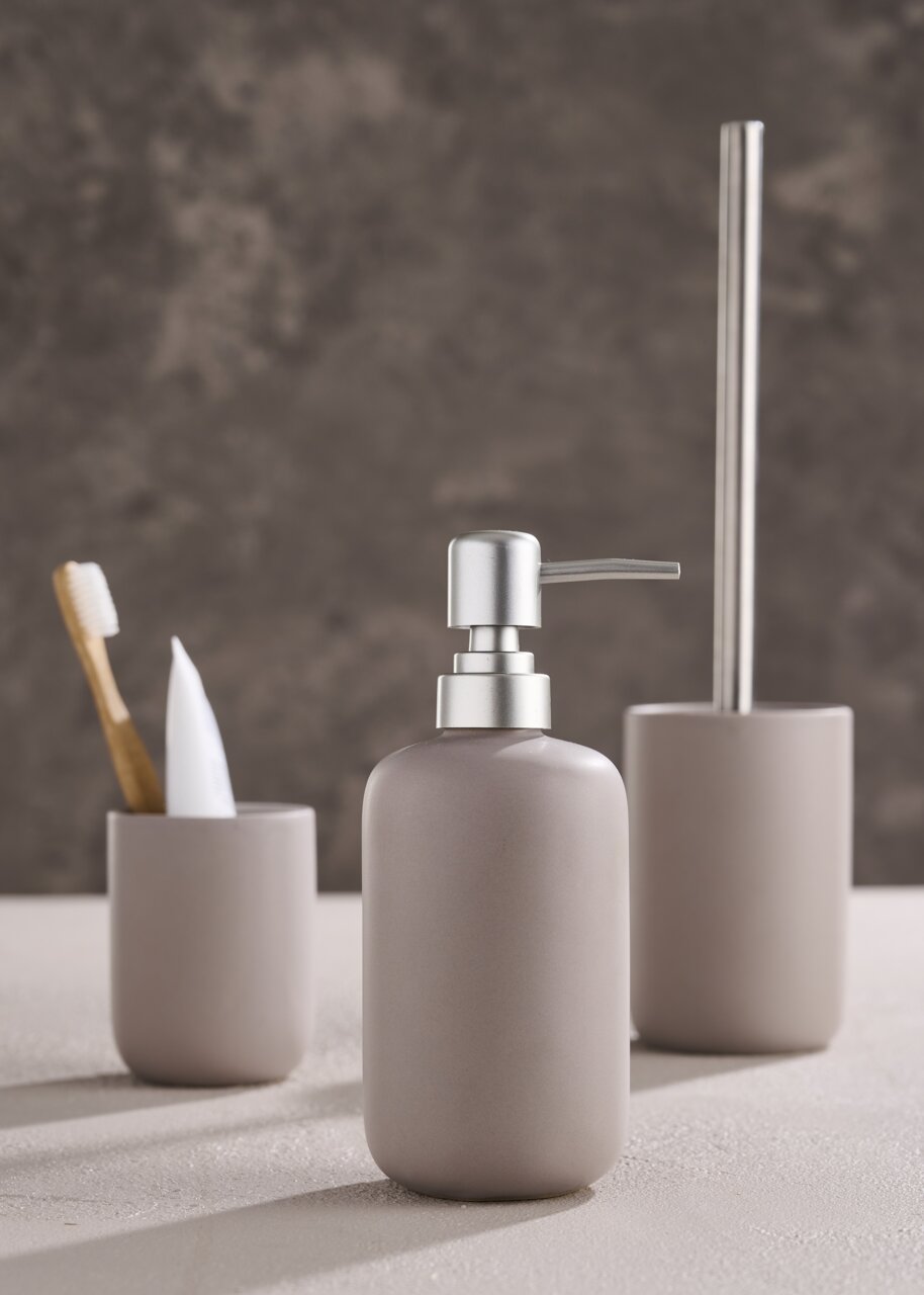 Day Badset 3-tlg. Modernes dreiteiliges Badset in neutralen Tönen, bestehend aus Seifenspender, Zahnbürstenhalter und Toilettenbürstenhalter, aus seitlicher Perspektive fotografiert.