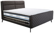 Seitliche Ansicht eines eleganten Boxspringbetts mit gestepptem Kopfteil und sichtbaren Federkernschichten.