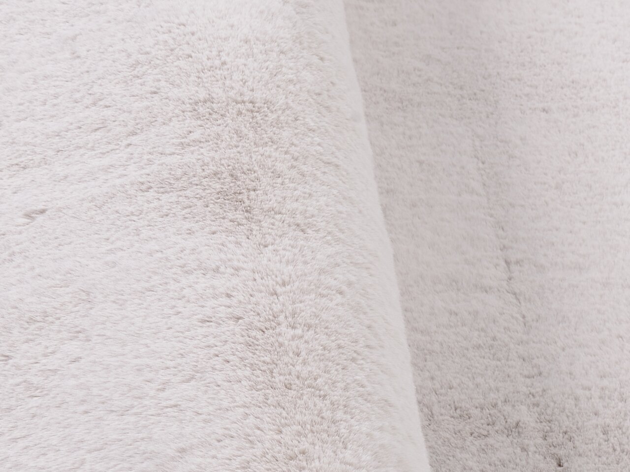 Nahaufnahme eines weißen Fellteppichs mit weicher Textur, seitliche Perspektive