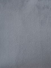 Nahaufnahme einer grauen Stofftextur, möglicherweise Polsterung eines Armlehnstuhls