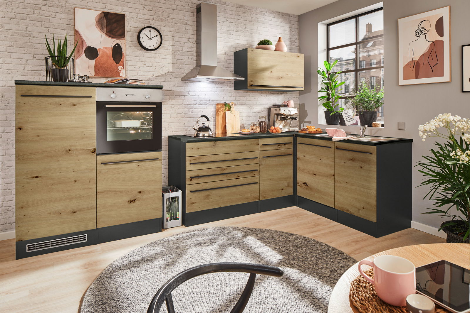 Moderne Küche mit Eckunterschrank in Holzoptik, fotografiert aus einer leicht erhöhten Perspektive. Die Küche verfügt über einen eingebauten Ofen, eine Dunstabzugshaube und eine Spüle, umgeben von stilvollen Dekorationen und Pflanzen.