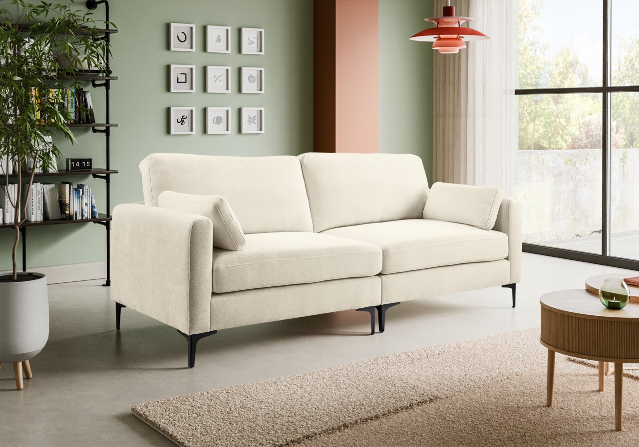 MID.YOU Sofa 3,5-Sitzer VENTI Beiges, modernes 3-Sitzer-Sofa mit Stoffbezug, breiten Armlehnen, zwei Rückenkissen und schwarzen Metallfüßen im Wohnzimmer; Perspektive: frontale Ansicht leicht von links.