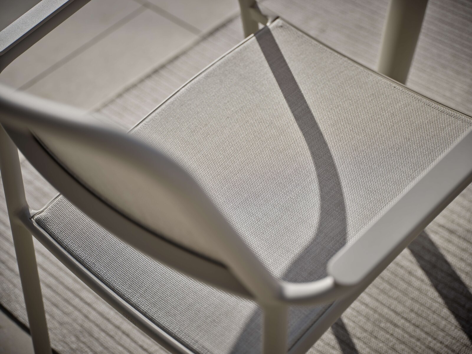 Nahaufnahme eines Stapelsessels aus Metall mit Textilbespannung, von oben betrachtet.