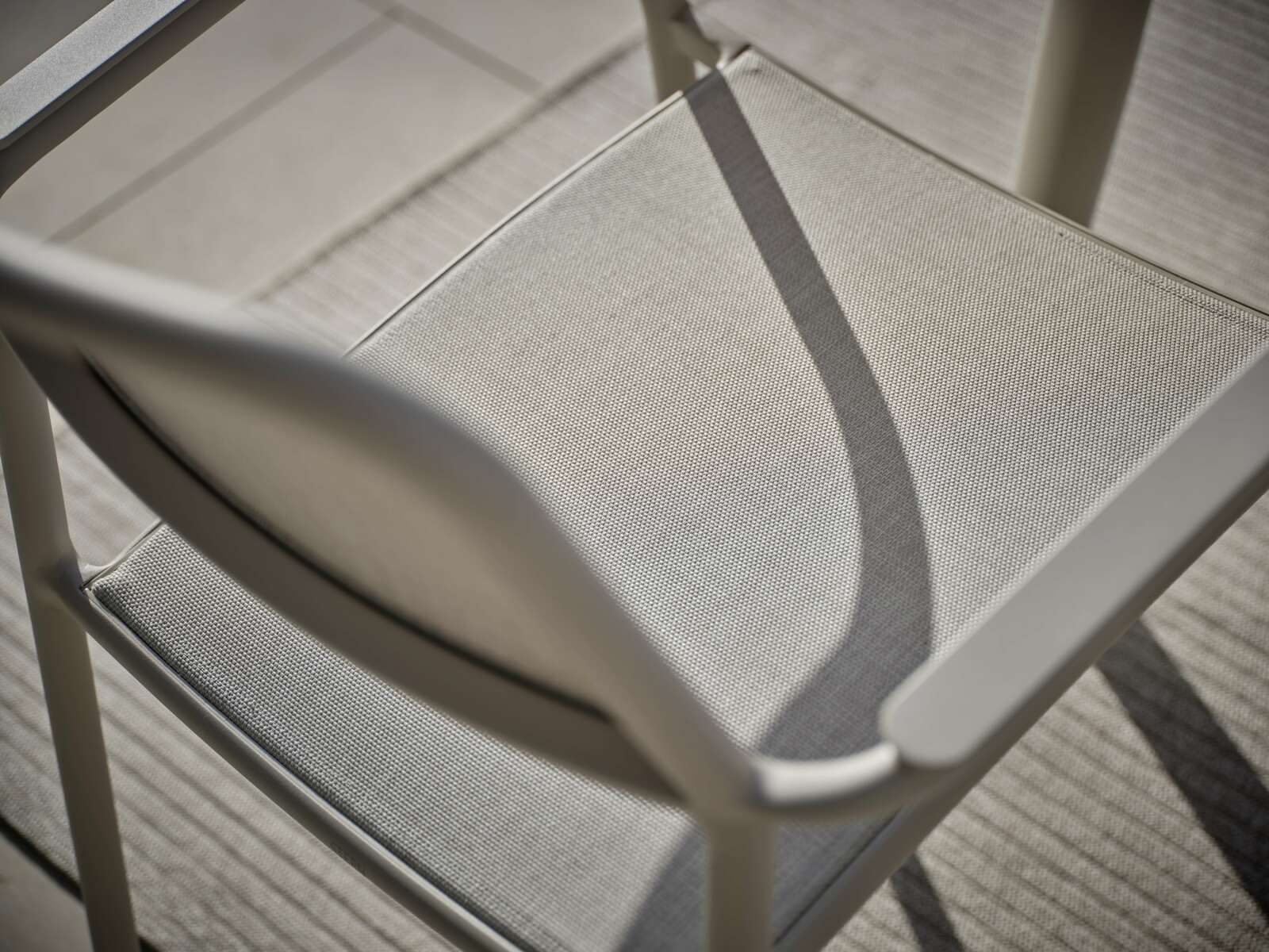 Nahaufnahme eines Stapelsessels aus Metall mit Textilbespannung, von oben betrachtet.