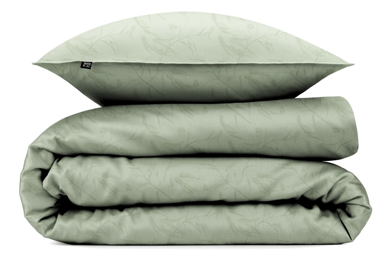 Grüne Bettwäsche mit dezentem Blattmuster, bestehend aus einem Kissenbezug und einem gefalteten Bettdeckenbezug, seitliche Perspektive