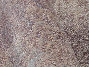 Nahaufnahme eines Designer Teppichs mit melierter Textur in Beige- und Grautönen, seitliche Perspektive