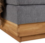 Nahaufnahme der Ecke eines Boxspringbetts mit grauem Stoffbezug und Holzrahmen.