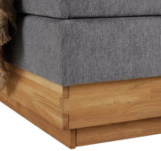Nahaufnahme der Ecke eines Boxspringbetts mit grauem Stoffbezug und Holzrahmen.