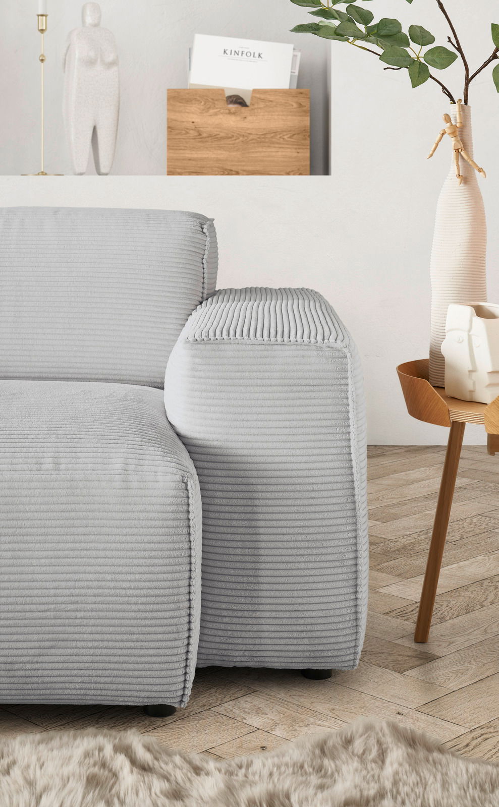 Graues Sofa mit geripptem Stoffbezug, Nahaufnahme der Armlehne von der Seite, mit modernem Dekor im Hintergrund.