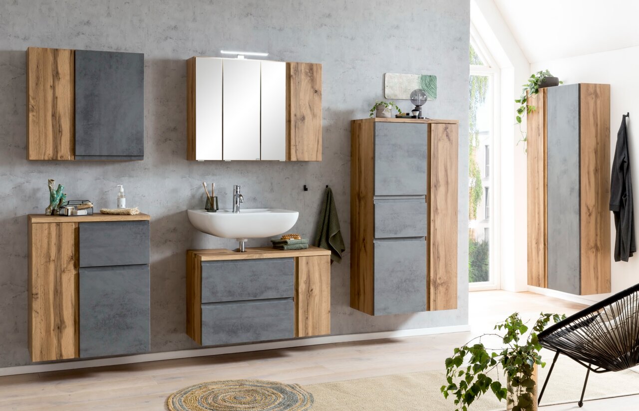 Moderner Waschbeckenunterschrank in Holzoptik mit grauen Fronten, links im Bild, Teil eines stilvollen Badezimmersets.