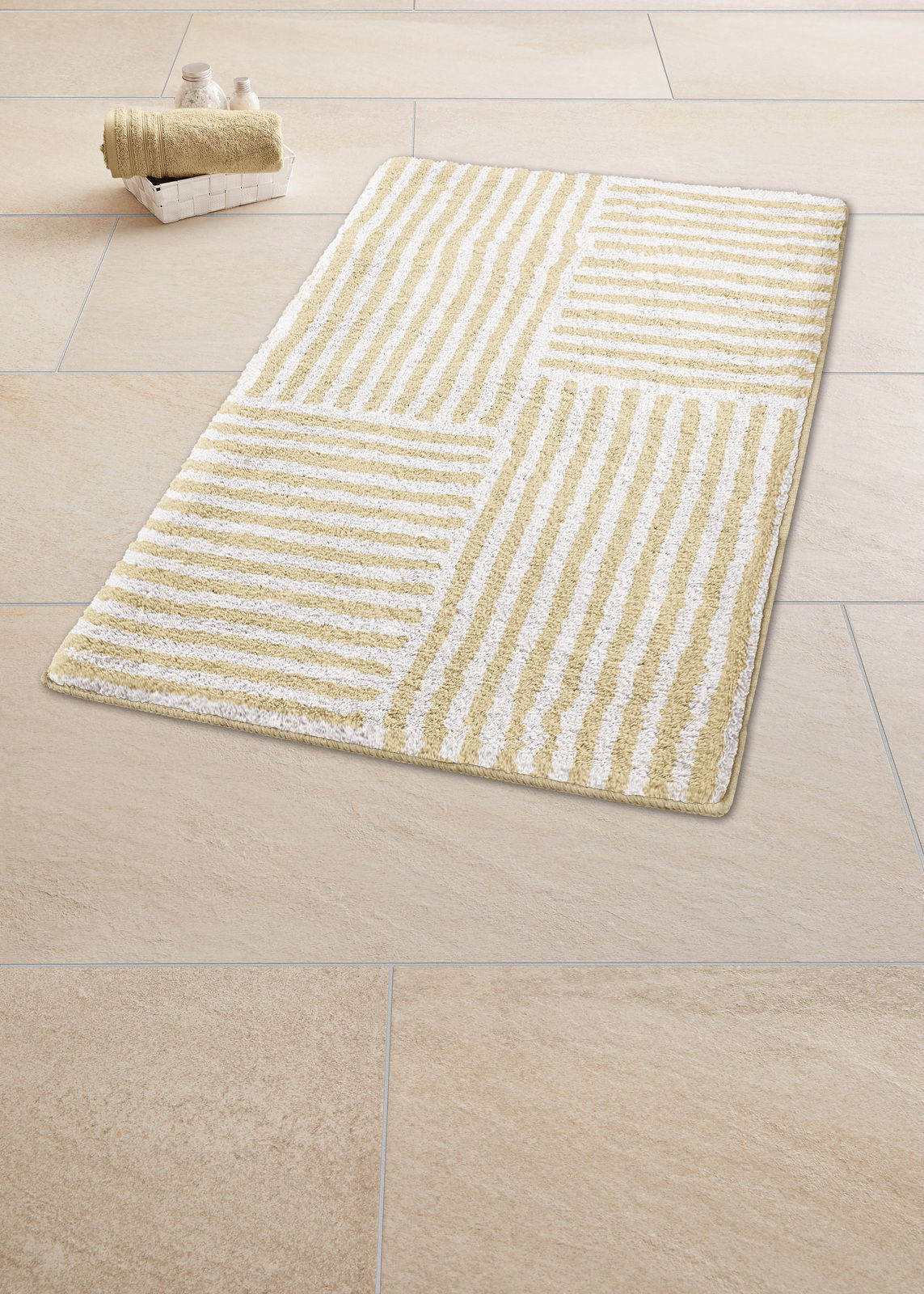 Beige-weißer Badteppich mit Streifenmuster auf Fliesenboden, perspektivisch von oben fotografiert.