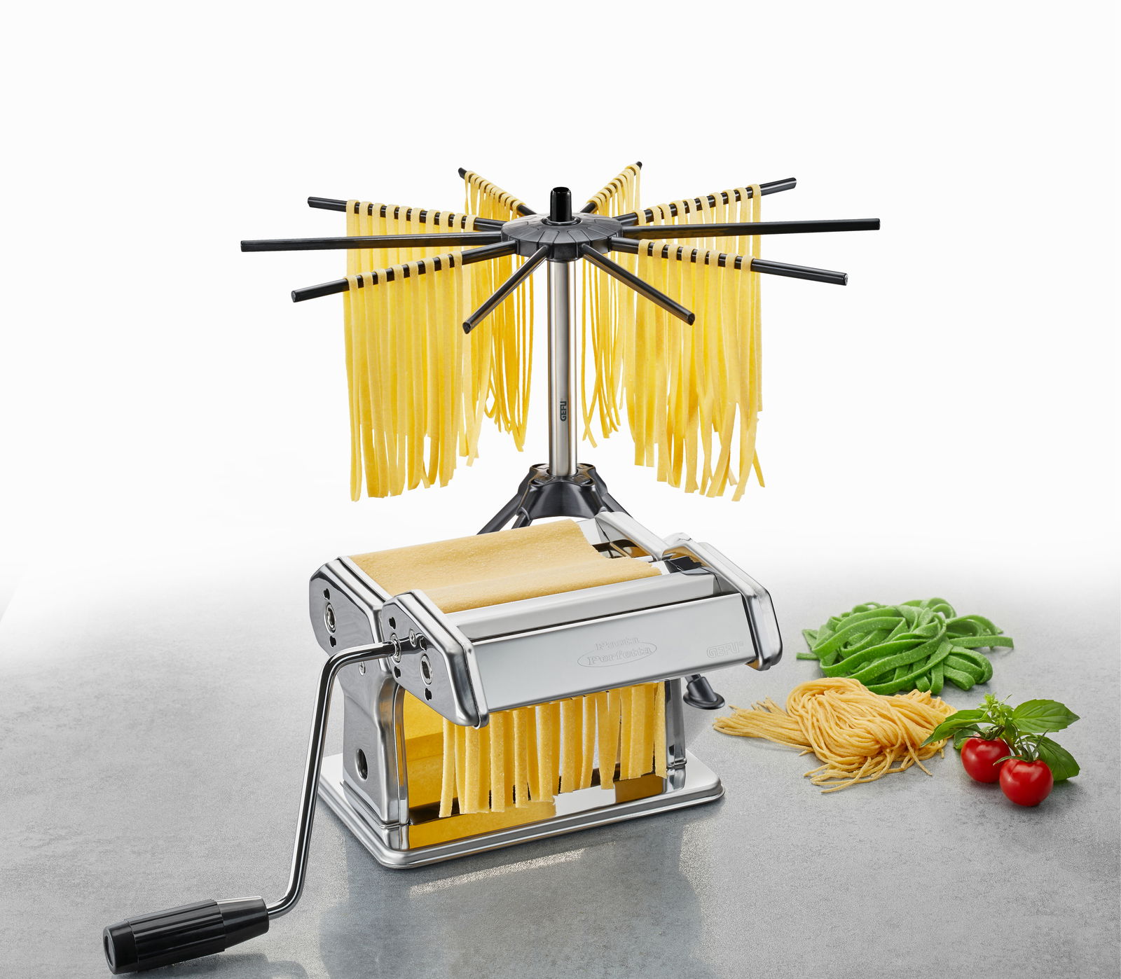 Pasta-Set mit Nudelmaschine und Trockner, seitliche Perspektive, frische Nudeln und Zutaten im Hintergrund