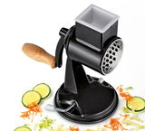 Trommelreibe CLASSIC in schwarz, seitliche Perspektive, mit Holzgriff und Gemüse in Scheiben und Streifen.