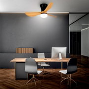 Moderner Deckenventilator mit drei Holzflügeln, schwarzem Gehäuse und integriertem LED-Licht, montiert an der Decke über einem minimalistischen Büroarbeitsplatz; Ansicht leicht von unten in Frontalperspektive